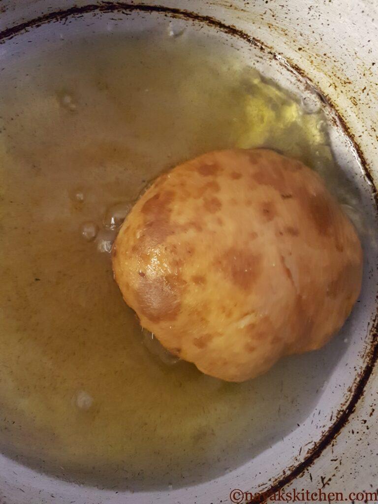 Turning the poori over to fry other side
