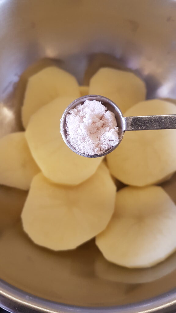 Adding salt to sliced potatoes