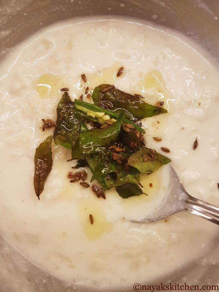 Adding the tempering over the curd-beaten rice mixture
