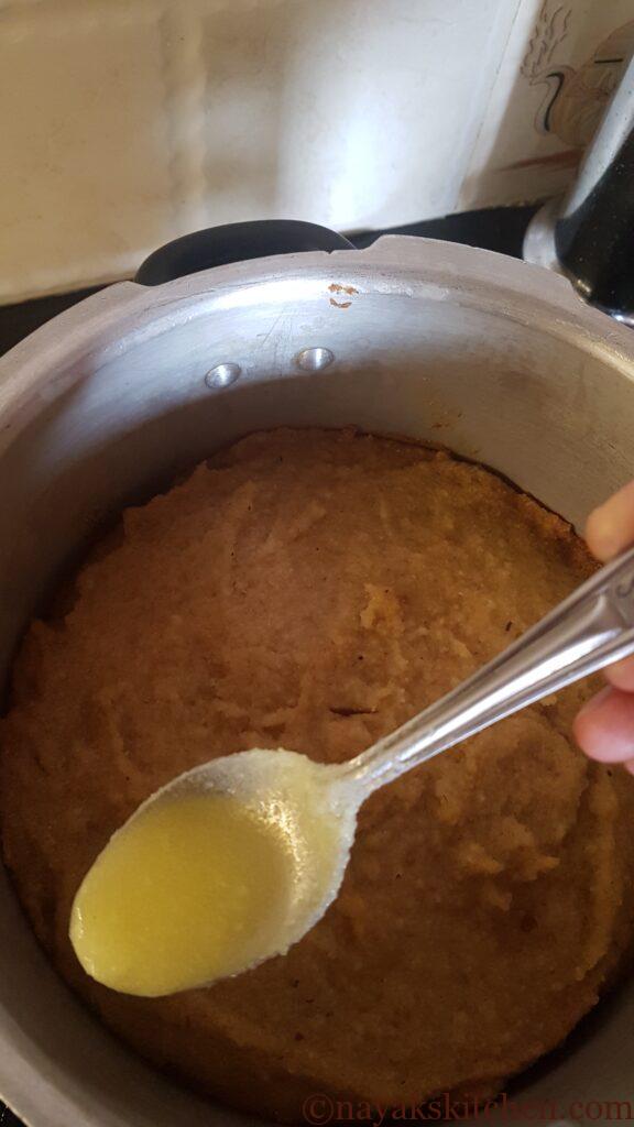 Pouring ghee along the sides of the cake to brown further