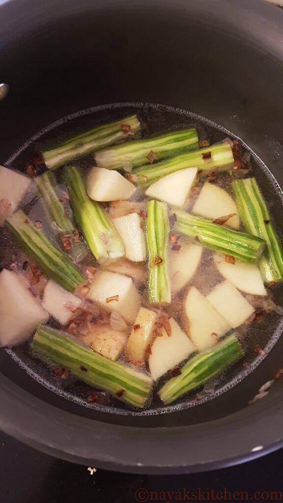 Adding water to cook drumsticks and potatoes