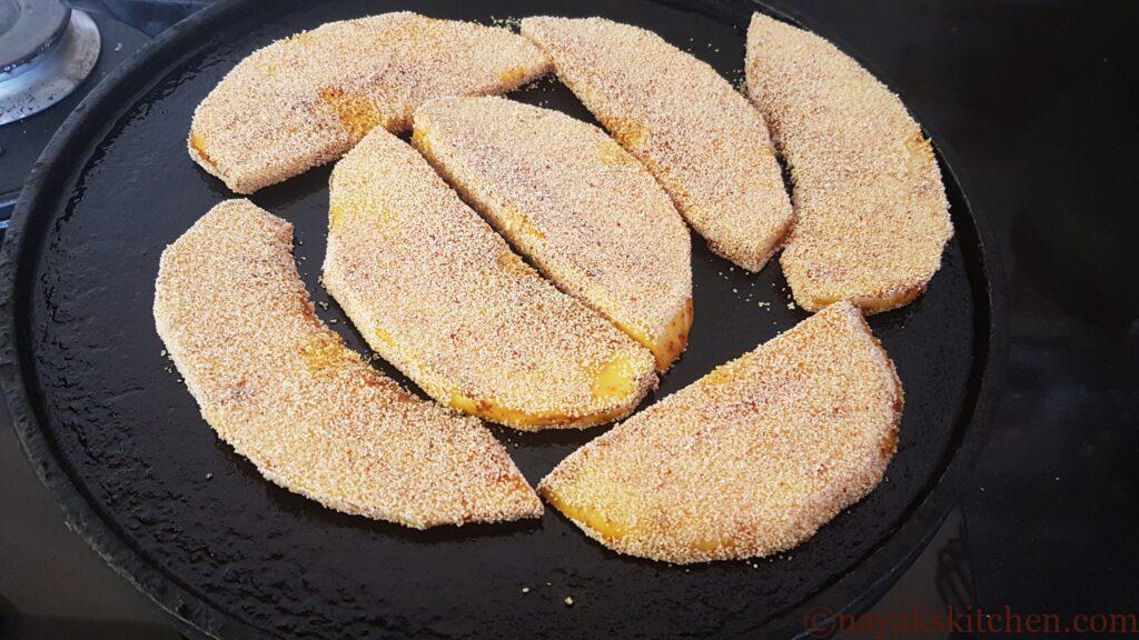 Placing rava coated breadfruit pieces on griddle