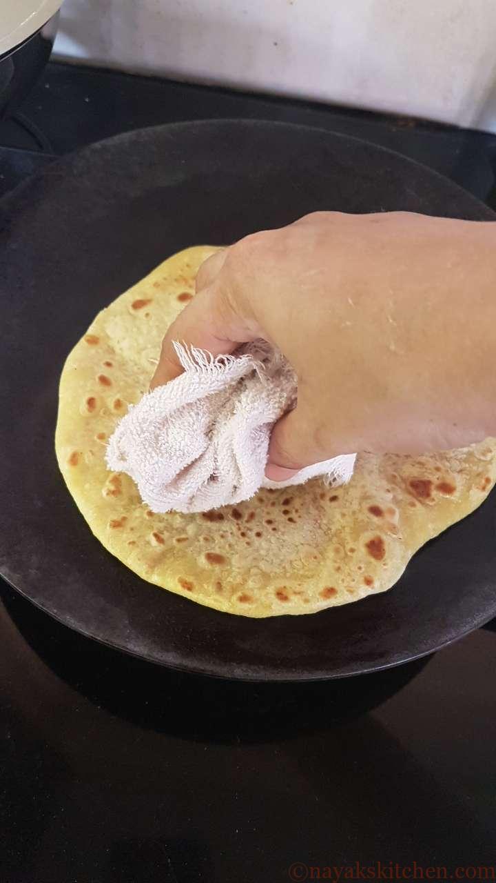 Patting puran poli with a cloth to puff it up