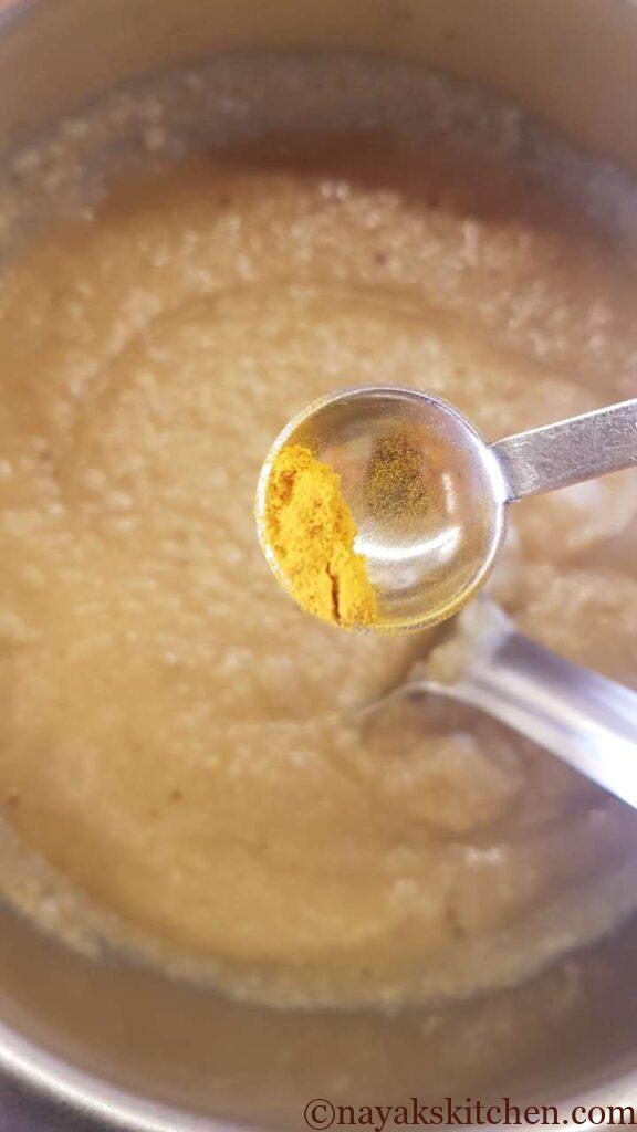 Adding turmeric powder to jackfruit idli batter