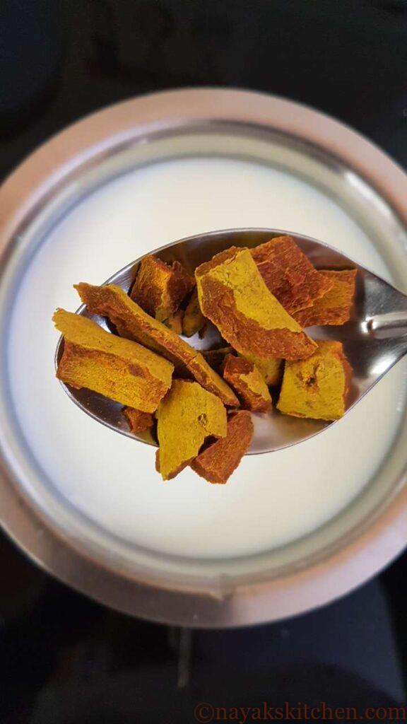 Adding pieces of haldi roots to milk