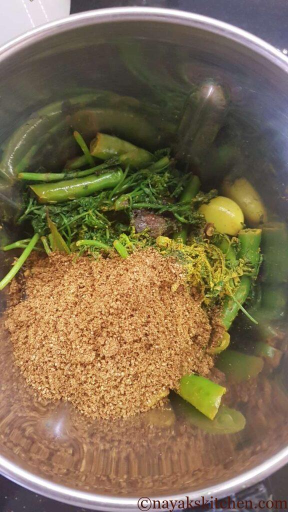 Adding spice powder and green masala ingredients to mixie jar.