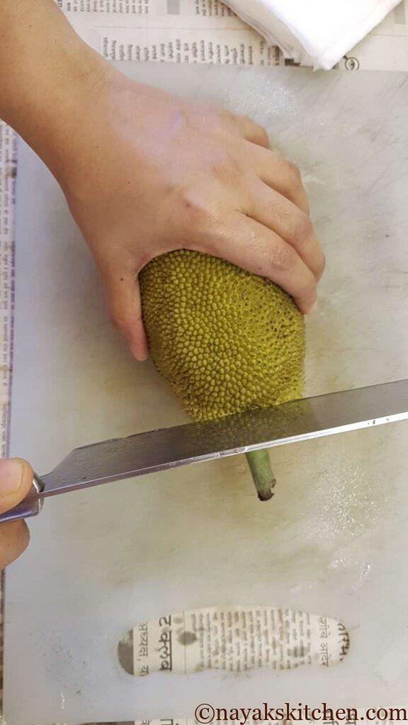 (How to cut a raw jackfruit?) Chopping the stem or stalk of unripe jackfruit 